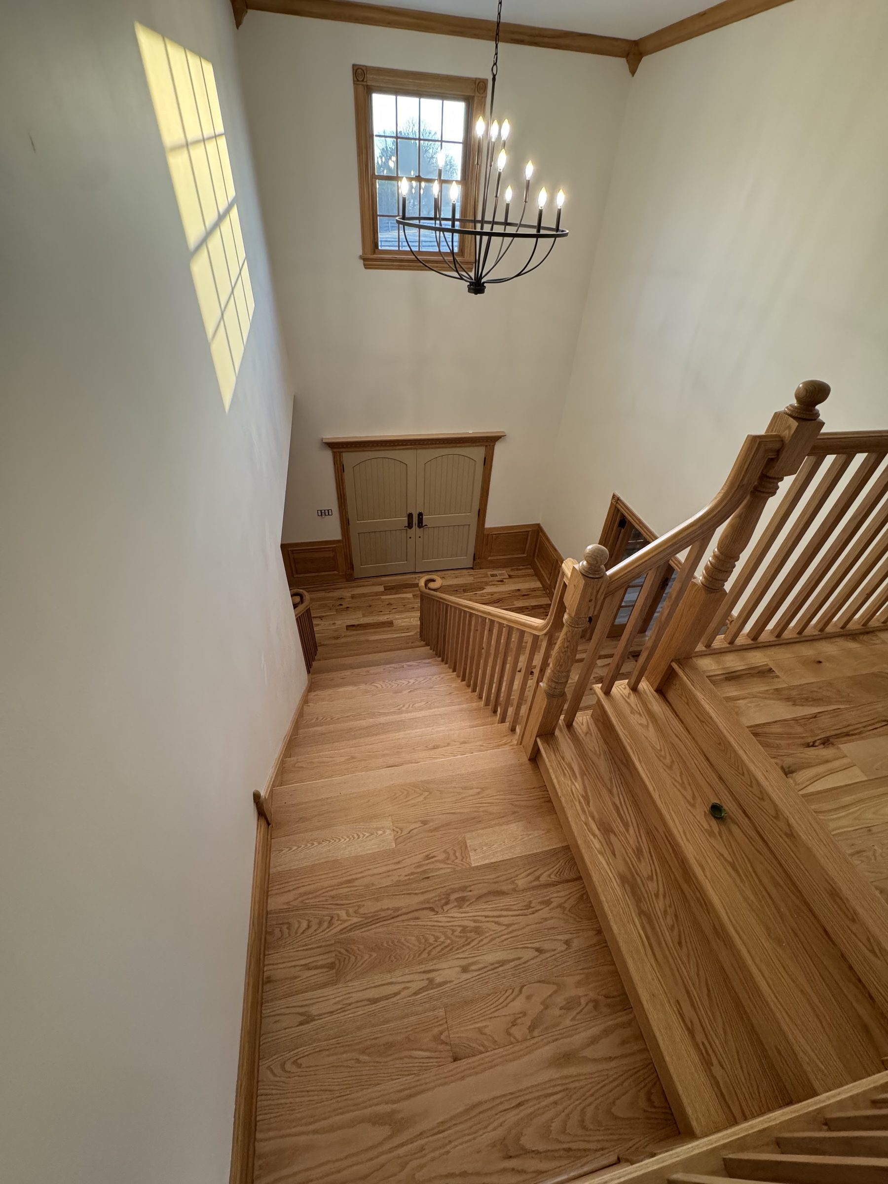 Stair landing with chandelier and oak fixtures